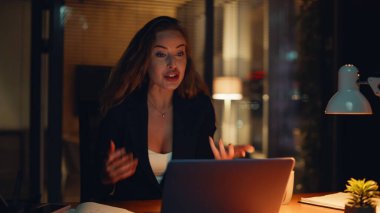 Neşeli iş kadını videosu akşam şirketinin ofisinde çalışıyor. Profesyonel mutlu kadın internette el kol hareketi yapıyor. Gülümseyen strateji uzmanı uzaktan kumandalı konferansta