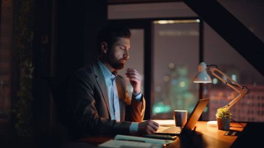 Geç saatlere kadar bilgisayar yazıp kahve yudumlarken ofis masasına yakın çekim yapıyor. Sakallı, kendine güvenen şirket çalışanı iş yerinde evrakları karıştırıyor. Ciddi bir iş adamı dizüstü bilgisayar işi yapıyor. 