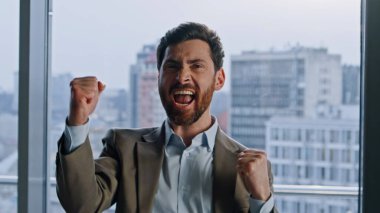 Şirketin kazananı cam duvarların iç portresinden çok memnun. Duygusal iş adamı iş başarısını kutluyor. Çok mutlu bir yönetici kazanan bir anlaşma. Koridorda tek başına neşeli bir şekilde el kol hareketi yapıyor. 
