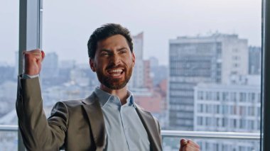 Neşeli şirket lideri duygusal olarak yakın plan görüntüsünde tezahürat yapıyor. Muzaffer menajer heyecanını göstermek için kollarını kaldırıyor. Zengin, kendine güvenen yönetmen cam duvarlar dolabında finansal ödülün keyfini çıkarıyor.