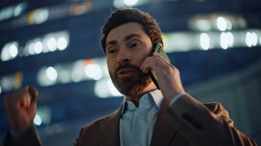 Memnuniyetle girişimci konuşan mobil cihaz Alacakaranlık Portresi 'nde duruyor. Neşeli yönetici, mutluluğu ifade eden olumlu bir güncelleme alıyor. Kendinden geçmiş patron telefon konuşmasında başarıdan zevk alıyor.