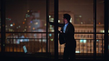 Fazla mesai müdürü gece odasında cep telefonu uyarısını kontrol ediyor. Rahatlamış adam karanlık siluet panoramik pencere ofis alanında akıllı telefon mesajları okuyor. Şık patron iş yerinde cep telefonu arıyor. 