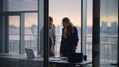 Ofis penceresinde duran kendine güvenen ortaklar iş ortaklığını tartışıyor. Ciddi ve zeki meslektaşlarımız ortak projede el sıkışmayı kabul etti. Birkaç iş arkadaşı özel odada birlikte çalışıyor.