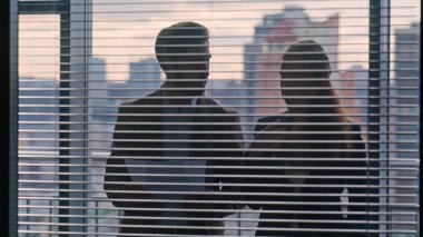 Kendine güvenen iş ortakları, özel atmosfer sohbetleri yakın çekim. İki rahat iş arkadaşı büyük vitrin ofisinde duran kağıtları inceliyor. Siluet meslektaşları sözleşmeyi tartışıyorlar