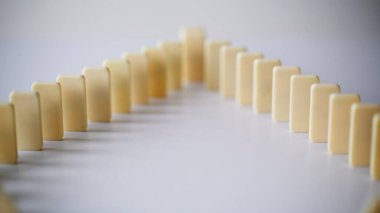 Domino yapısı düz yüzeyde geometrik yapı oluşturuyor. Sessiz dengeyi yakın plan olarak gösteriyor. Grup oyun taşları içeride sakin konsantrasyonu yansıtan hizaya dizildi. Stratejik planlama simetri kavramı.