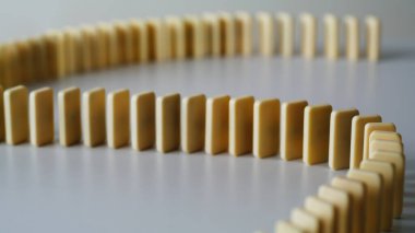 Işık yüzeyinde duran dalgalı domino taşları yakın plan. Oyun, sakin estetik çizimler yaratmak için pürüzsüz tuğlalar örüyor. İçerideki masaya dikdörtgen şeklinde oyuncak blokları yerleştirin. Zincir etkisi reaksiyon konsepti.