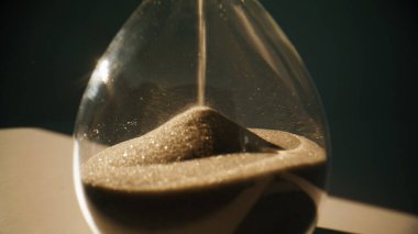 Kum saatine düşen kum, akşam vakti yanan odada masada duruyor. Makro manzaralı altın taneleri zarif saatin içinde saniyeleri sayıyor. Zaman akışını gösteren şeffaf bir saat. Klasik dekor kavramı