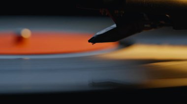 Macro view iğnesi vinil pikapta şarkı söyleyen oluklara dokunuyor. Siyah disk, klasik müzik eşliğinde retro turntable üzerinde dönüyor. Karanlık odada klasik ses ekipmanları. Eski okul atmosferi.