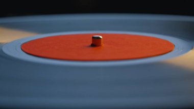 Yakın çekim retro kaydı dairedeki eski pikapta dönüyor. Makro görünüm parlak vinil kapalı alandaki klasik gramofonda sakin bir melodi çalıyor. Klasik müzik ekipmanları şarkı çalıyor. Zamansız teknoloji.