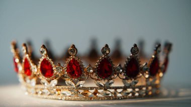 Kapalı alan boşluğuna yerleştirilmiş süslü bir taç. Değerli nesne zengin simetriyi ve kraliyet bağlamını gözler önüne seriyor. Parlak kırmızı taşları olan güzel bir mücevher parçası. Geleneksel monarşi sembolü kavramı.