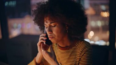 Overtime worker calling at office frustrated conversation closeup. Exhausted african american businesswoman finish stressful smartphone talk. Worried woman hung up cellphone touching temples at night