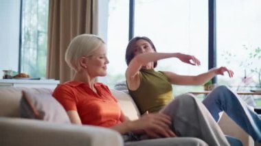 Kaygısız kızlar kanepeye düşüp evde eğleniyorlar. Gülümseyen lgbt çifti, keyifli bir hafta sonu geçirmek için oturma odasında beşlik çakıyor. Koltukta oturan rahat mutlu insanlar. Mutluluk kavramı 