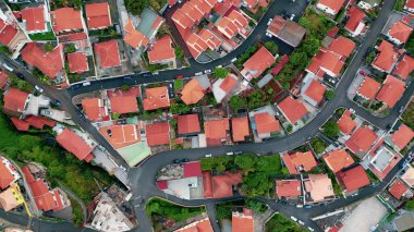 Red rooftops cover residential quarter in Portuguese town. Drone view curved roads compact settlement. Beautiful tiled roof buildings standing in rows forming residential district. Urban neighborhood