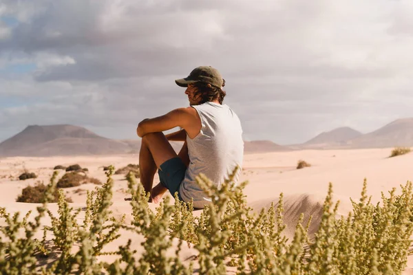 Молодий Чоловік Кепкою Сидить Піску Пустелі Корралехо Фуертевентурі Споглядаючи Горизонт — стокове фото