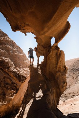 Fuerteventura 'daki çölün kumtaşı kanyonunun kaya oluşumlarını keşfeden adam.