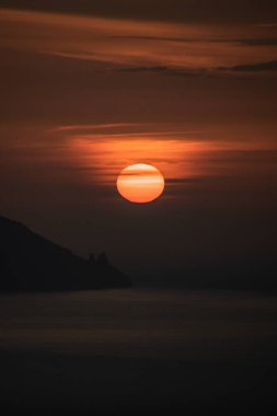 Ufukta büyük kızıl bir güneş olan gün batımı denizin üzerinde ve Tenerife adasından La Gomera 'nın kayalıklarının yanında saklanıyor.
