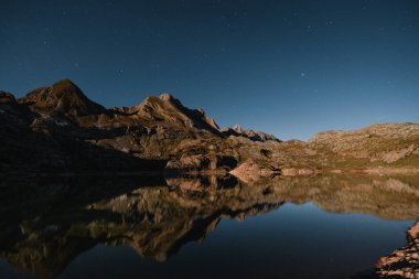 İbon 'un ya da Estanes Gölü' nün gece manzarası ay ve yıldızlı gökyüzü ile aydınlanıyor, Pireneler 'deki Candanch yakınlarında.