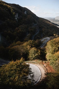 Ray of light illuminates the curve of a mountain pass road surrounded by forest in Navarra, Euskal Herria clipart