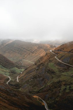 Winding mountain road in the misty Puerto de Estacas de Trueba, Valles Pasiegos, Spain clipart