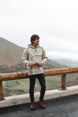 Young Man Standing at a Scenic Mountain Viewpoint clipart