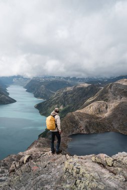 Hiker explores Norway's famous Besseggen ridge with sweeping fjord views. clipart