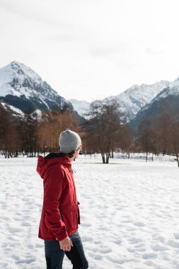 Kırmızı ceketli bir adam kışın Pireneler 'in karlı dağlarına hayran.