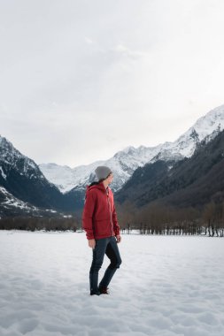 A man enjoys the serene beauty of the snowy Pyrenees with a mountain backdrop clipart