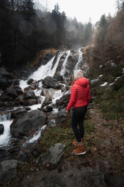 Pireneler 'in sisli ormanındaki şelaleye hayran bir kadın.
