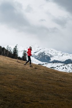 Woman Hiking on Snowy Pyrenees Trail in Red Jacket with beautiful views clipart