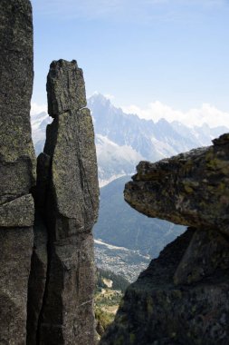 Dramatic rock formations frame a view of Mont Blanc and Chamonix during a clear day clipart