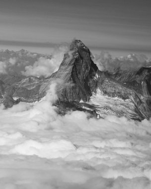 Iconic Matterhorn peak towers above a sea of clouds, captured in stunning black and white. clipart