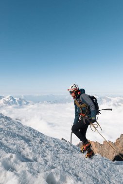Bir dağcı arka planda Cervino Alpleri ile karla kaplı yamaçlara tırmanır.