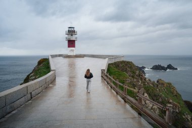 Bir gezgin, dramatik okyanus manzaralarıyla çevrili ikonik Cape Ortegal Deniz Feneri 'ne yaklaşıyor.