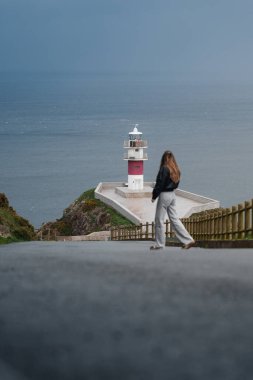 A serene road leading to Cabo Ortegal Lighthouse, Galicia, with moody skies and coastal beauty clipart