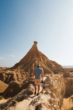 A traveler approaches the iconic Castildetierra rock formation in Bardenas Reales, showcasing the unique and rugged desert beauty of this Spanish natural landmark. clipart