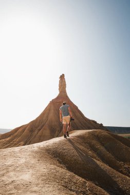 Bir gezgin, Bardenas Reales 'teki ikonik Castildetierra oluşumuna yaklaşır. Çarpıcı şekilleri ve kurak güzelliğiyle karakterize edilen doğal bir mucizedir..