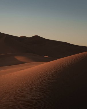 Merzouga, Fas 'ta batan güneşin sıcacık parıltısıyla yıkanan erg chebbi' nin desenli kum tepelerinin çarpıcı görüntüsü.