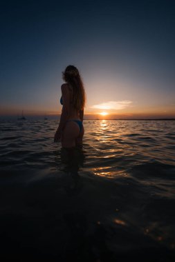 Denizde duran ve Akdeniz 'in üzerinde gün batımını seyreden bir turist.