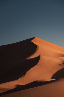 Merzouga, Fas yakınlarındaki Sahara çölündeki erg chebbi kumullarının üzerinde güneşin çarpıcı bir şekilde batışı.