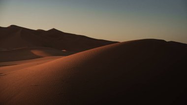 Merzouga, Fas yakınlarındaki Sahara Çölü 'ndeki erg chebbi kumullarının üzerinden güneşin çarpıcı bir şekilde batışı.
