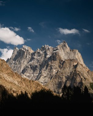 Engebeli dağ zirveleri berrak mavi gökyüzünün altında yükseliyor.