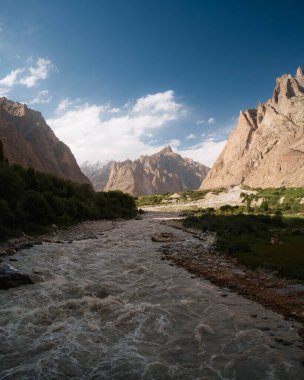 Nehir, açık bir gökyüzünün altındaki yüksek dağlarla çevrili Hushe Vadisi 'nden akar.