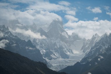 Karakoram dağ sırasındaki dramatik tepeler ve bulutlarla çevrili Baltoro buzulunun görkemli manzarası, Pakistan
