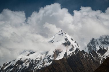Baltoro buzulunun görkemli kar zirveleri Karakoram, Pakistan 'da bulutların arasından yükseliyor.