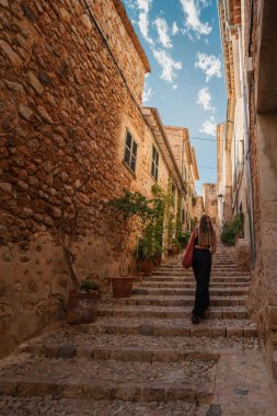 Fornalutx, Mallorca 'nın taş basamaklarında huzurlu bir gezinti. Geleneksel Akdeniz evleri ve yemyeşil alanlar huzurlu bir seyahat deneyimi yaratıyor..