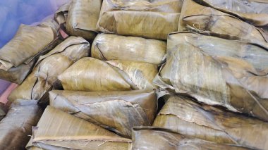 Muz yapraklarına sarılmış sebzelerle dolu pirinç keki.