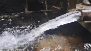 Temiz su bir borudan bir su deposuna hızla akıyor.