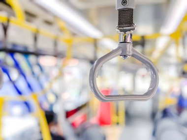 Seyahat sırasında yolcuların güvenliğini ve rahatlamasını sağlamak için toplu taşıma araçlarının içindeki el tutucunun izole edilmiş odağı. Bulanık arkaplan 