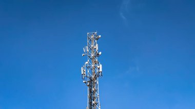Telekomünikasyon kulesi bulutlu ve mavi gökyüzünün altında. Kablosuz iletişim ve bilgi teknolojisi kavramı