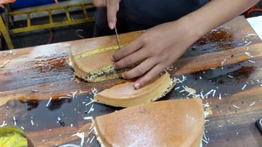 Sinematik çekim. Peynir, fıstık, çikolata ve tatlı sütle doldurulmuş Martabak Keju olarak bilinen tatlı peynirli tavada kızartılmış hamur işi. Endonezya mutfağının tanınmış yemeklerinden biri.
